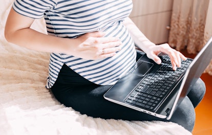 Pregnant woman working on laptop. Cropped image of pregnant businesswoman typing something on laptop. 