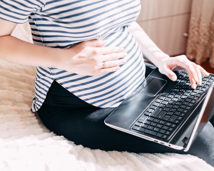 Pregnant woman working on laptop. Cropped image of pregnant businesswoman typing something on laptop...