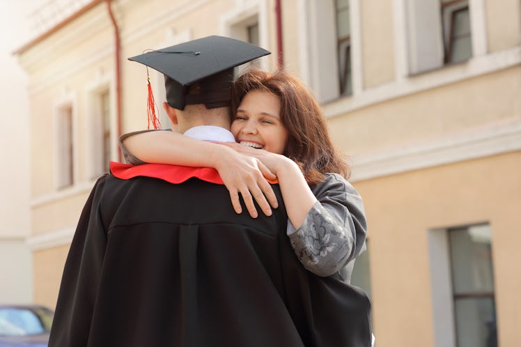 Happy Mother hugs her son student in graduation gown and a square cap after the graduation ceremony