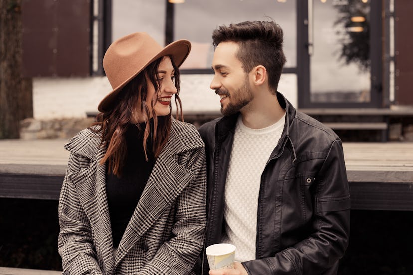 A man and a woman who are in a relationship, sitting, smiling and looking at each other