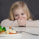 Toddler does not want to eat vegetable. Portrait of little girl refusing vegetable from plate in fro...