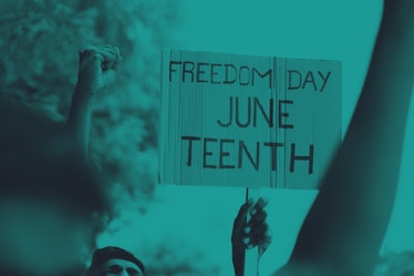 A cardboard sign that reads "Freedom Day Juneteenth" with fists raised up