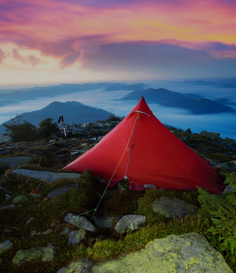 beautiful athlete's overnight stay with ultralight modern equipment on top of an alpine mountain wit...