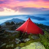 beautiful athlete's overnight stay with ultralight modern equipment on top of an alpine mountain wit...