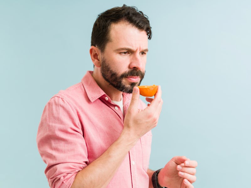Ill man can't smell because of anosmia sickness. Latin man with a loss of sense of smell holding an ...