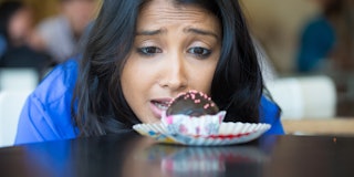 Closeup portrait of desperate woman in blue shirt craving fudge with pink sprinkles dessert, eager t...