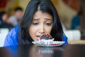 Closeup portrait of desperate woman in blue shirt craving fudge with pink sprinkles dessert, eager t...