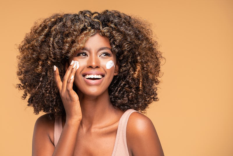 Beautiful afro woman with a cream on face. Skin care concept.