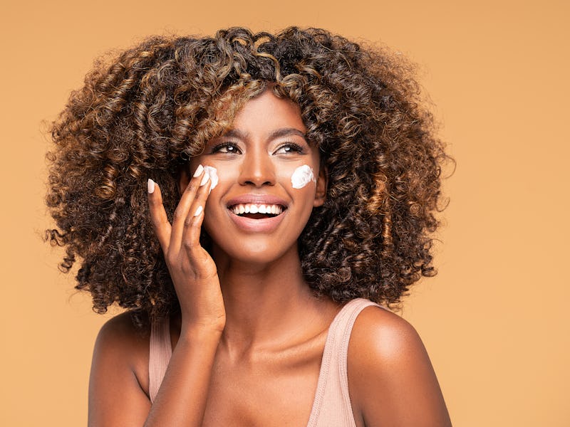Beautiful afro woman with a cream on face. Skin care concept.