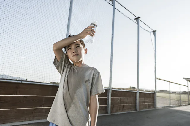 A boy tired out after practice wipes his sweaty head.