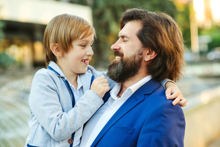 Handsome father hugging his little son outdoors. Stylish bearded man with child on a walk. Fashionab...