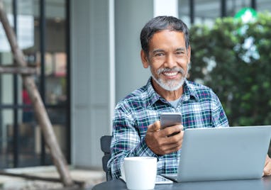 Smiling happy mature asian man with white stylish short beard using smartphone gadget serving intern...