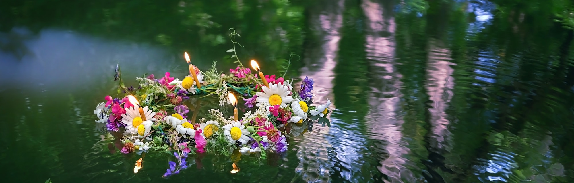 flowers wreath with burning candles in water. old national tradition, fortune telling for pagan holi...