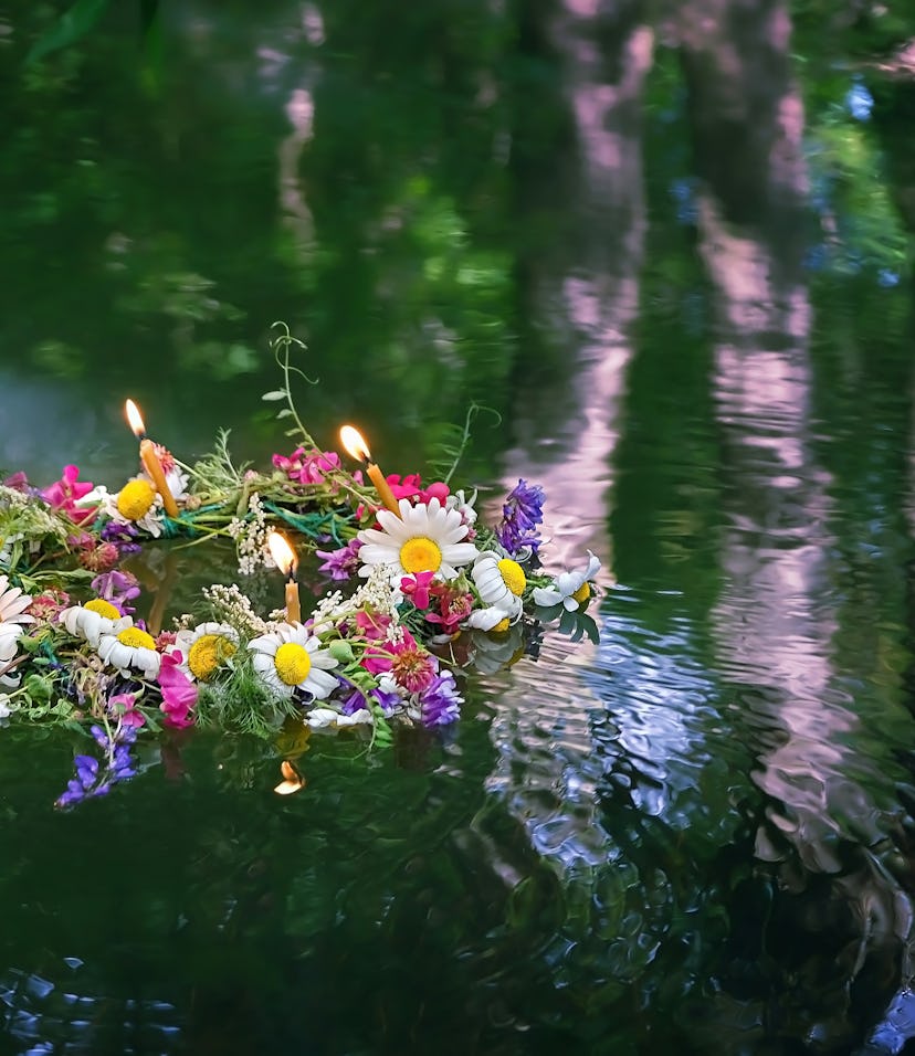 flowers wreath with burning candles in water. old national tradition, fortune telling for pagan holi...