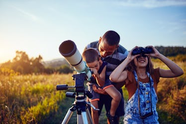 Father, daughter and son observing the sky with a telescope.