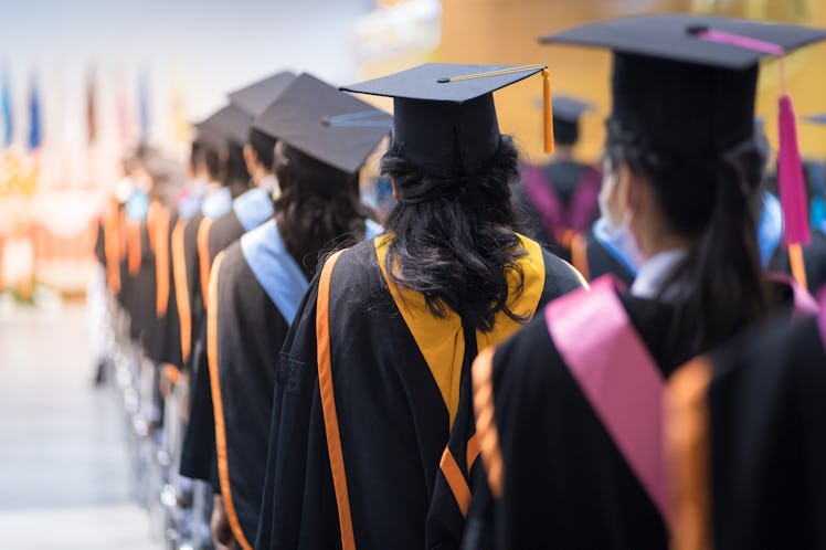 Rearview of the university graduates line up for degree award in university graduation ceremony. The...