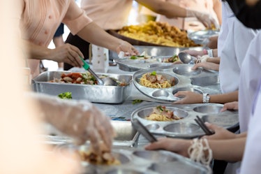 Cafeteria workers distributing free lunch to elementary school students.