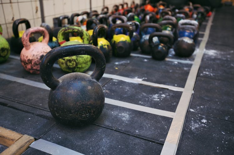 Different sizes of kettlebells weights lying on gym floor. Equipment commonly used for crossfit trai...