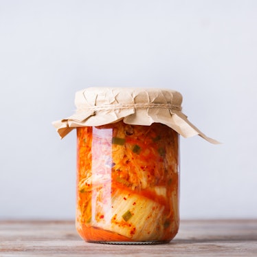 Homemade organic traditional korean kimchi cabbage salad in a glass jar on a wooden table. Fermented...