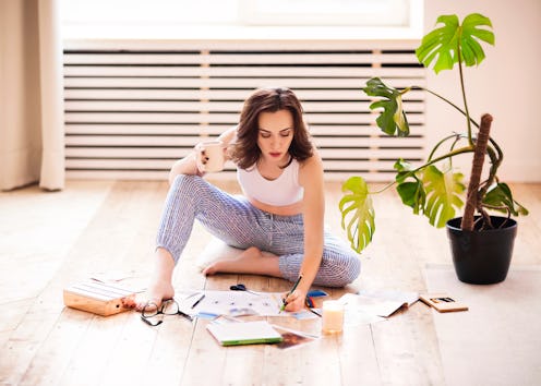 Young brunette woman creating her Feng Shui wish map using scissors. Dreams and wishes