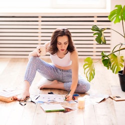 Young brunette woman creating her Feng Shui wish map using scissors. Dreams and wishes