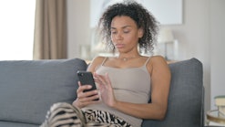 Black woman using smartphone on a couch