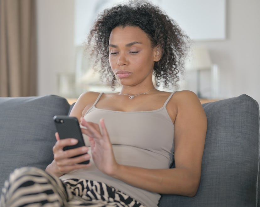 Black woman using smartphone on a couch