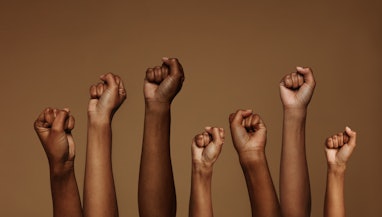 Cropped shot of hands raised with closed fists. Multiple hands raised up with closed fist symbolizin...