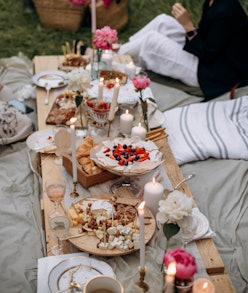 outdoor picnic feast. festive pallet table with desserts and snacks. people sitting near the table w...