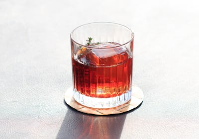 Italian Negroni Cocktail with sun shining through the glass and creating a long shadow.