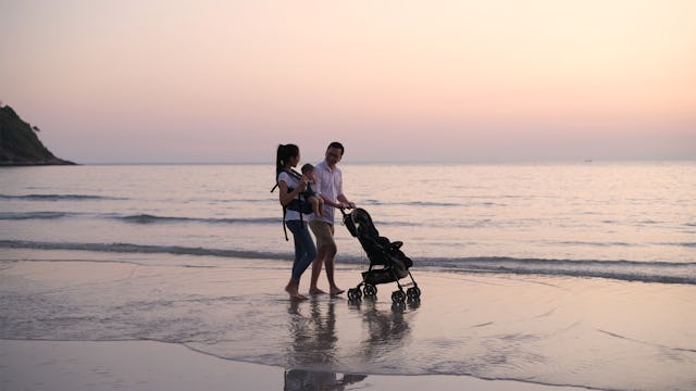 Parents are pushing the baby cart on the beach.
