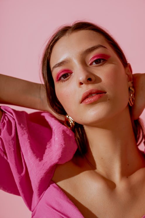 Close up beauty portrait of young beautiful woman with pink, fuchsia color eyeshadow makeup, flawles...
