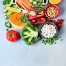Raw and healthy plant-based foods, including red pepper, chickpeas, and carrots.