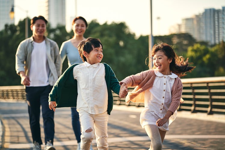 happy family with two children walking on pedestrian bridge in city park.