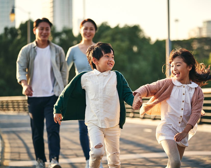 happy family with two children walking on pedestrian bridge in city park.