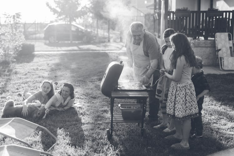 Grandfather teaching his grandchildren how to grill meal.