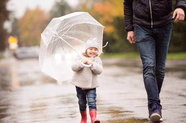 Dad and kid walking in the rain showing laughing together at a father's day riddle