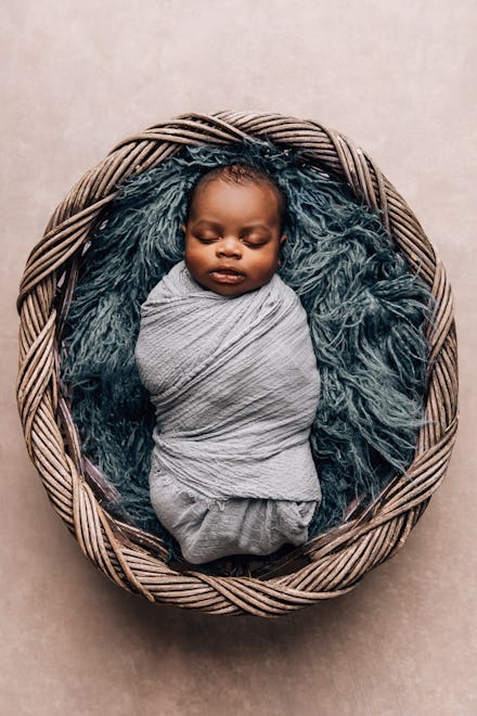sleepy swaddled newborn baby boy laying on a blue rug. Can you breastfeed a swaddled baby??