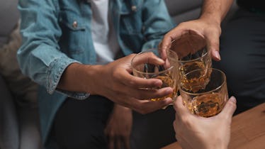 Close up group of friends toasting glasses of whisky.