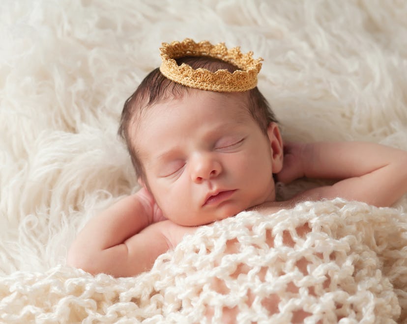 A sleeping newborn baby wearing a gold crown, tudor baby names