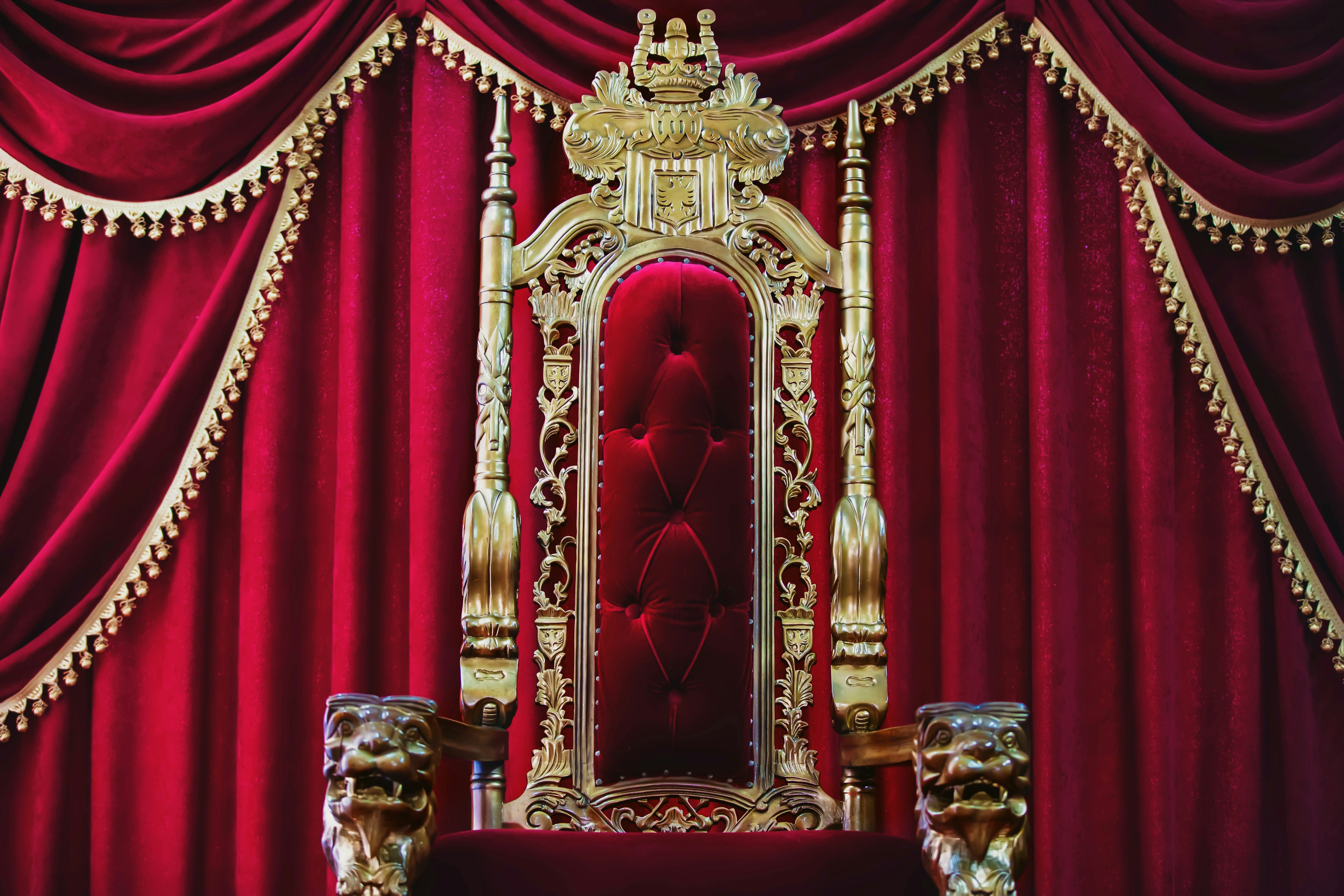 Part of the red royal chair against the background of red curtains. A place for a king. Throne