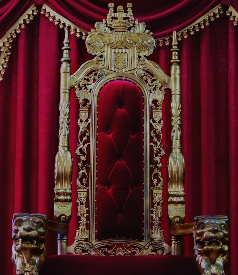 Part of the red royal chair against the background of red curtains. A place for a king. Throne