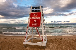 Lifeguard stand with no lifeguard on duty as the sun sets on lake Michigan.  Lighthouse beach, Evans...