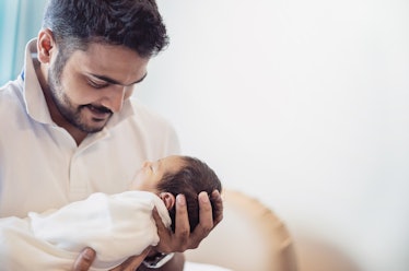 Closeup portrait of young asian Indian father holding his newborn baby with copy space. Healthcare a...