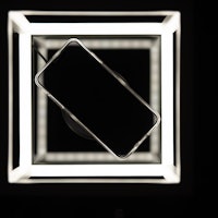 Mobile phone on wireless charger, black background with led lighting and reflections on the glass su...