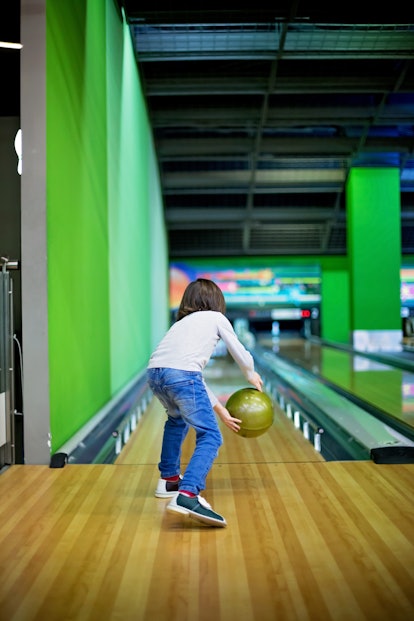 Young boy, playing bowling for the first time, indoors