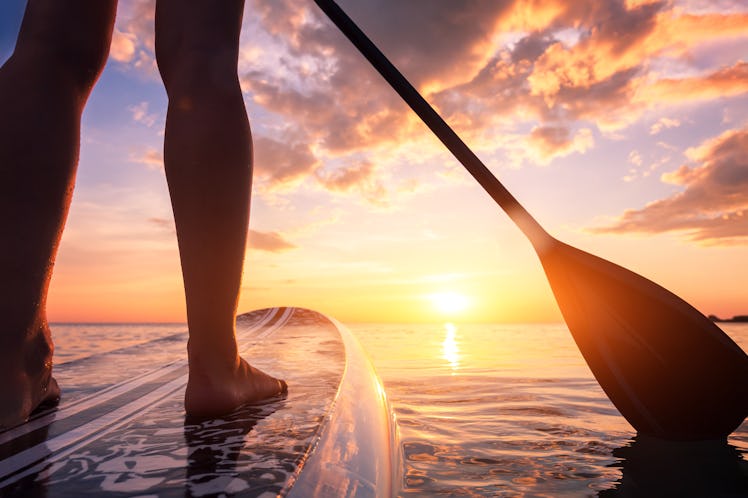 Stand up paddle boarding or standup paddleboarding on quiet sea at sunset with beautiful colors duri...