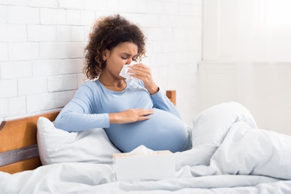 a sick woman sneezing while pregnant
