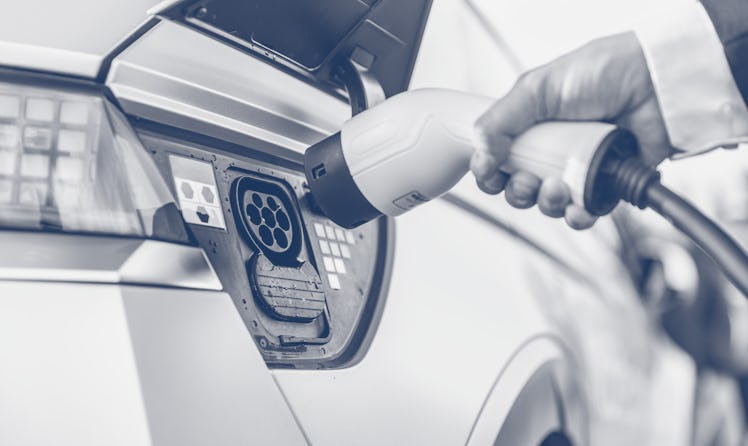 The driver of the electric car inserts the electrical connector to charge the batteries.