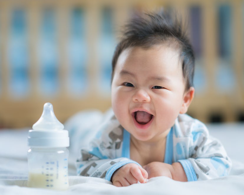 Asian baby smiles with a bottle of formula